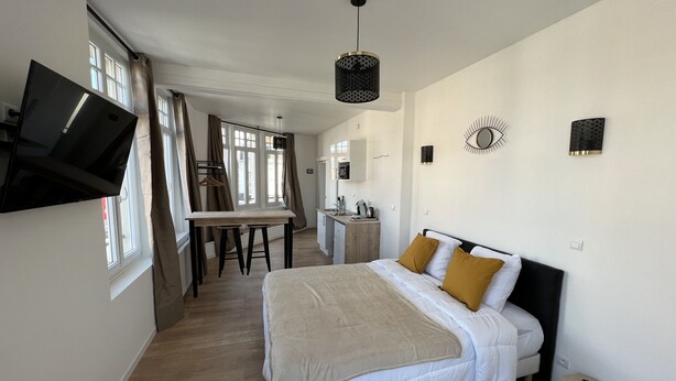 A bedroom with a bed, a desk, and a TV mounted on the wall. - La Suite Balnéo - 2p downtown Liévin (Liévin)