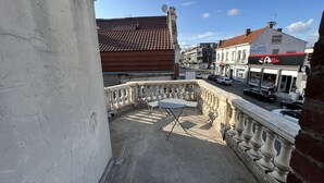 A balcony with a view of a street, a building with a tiled roof, and a restaurant named "Alibi". - La Suite Balnéo - 2p downtown Liévin (Liévin)