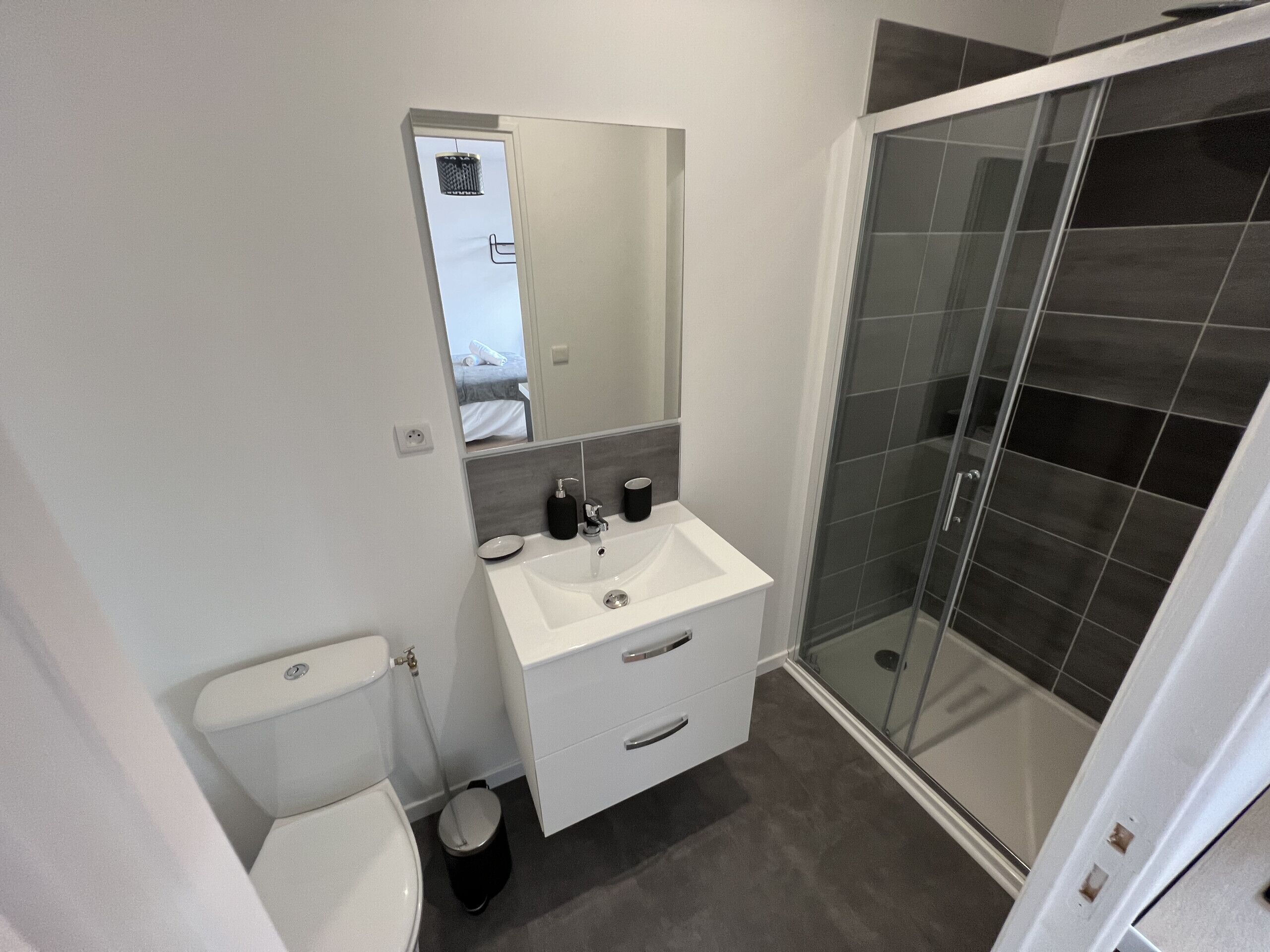 Een moderne badkamer met een wit wastafelmeubel, spiegel en toilet.