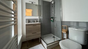 Une salle de bain moderne avec une douche à parois de verre, un meuble-lavabo en bois et des toilettes blanches.