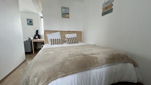 A neatly arranged bedroom with a large bed, a desk, and a chair.