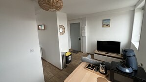A modern living room with a flat-screen TV, a coffee maker, and a wooden table.