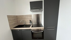 A modern kitchen with a black countertop, stainless steel appliances, and wooden cabinetry.