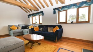 A living room with two sofas, a coffee table, and a rug. There are windows with curtains and a wooden ceiling. - Beachside holiday home  (Padstow)
