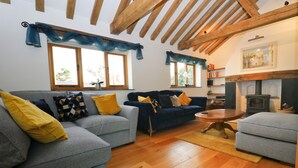 A living room with two sofas, wooden flooring, and a fireplace. - Beachside holiday home  (Padstow)