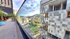 A high-rise building with a modern design, featuring a glass facade and a view of a cityscape with greenery and other buildings. - Seu aconchegante lar no centro carioca (Rio de Janeiro)