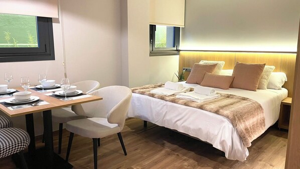 Ein Hotelzimmer mit einem Bett, einem Esstisch mit Stühlen und einem Fernseher.