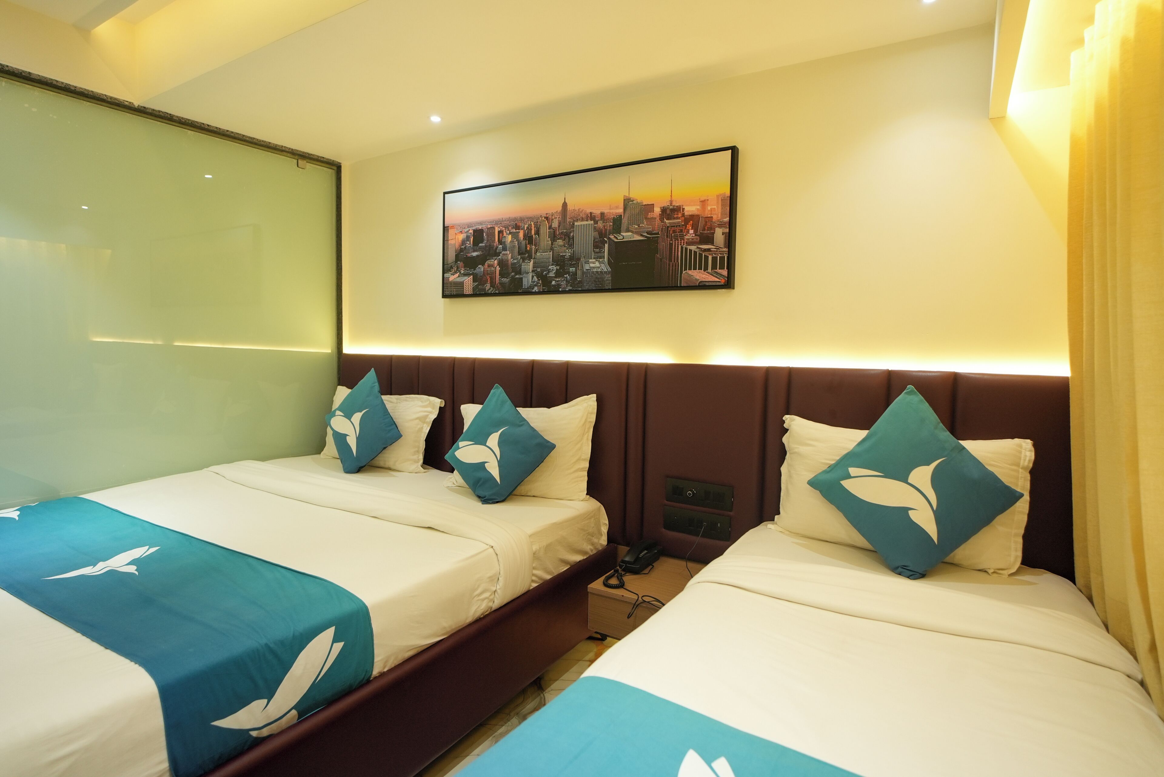 Habitación de hotel con dos camas, vista panorámica de la ciudad y una mesita de noche.