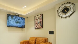 Una sala de estar moderna con un sofá, un televisor de pantalla plana, un reloj y una mesita.