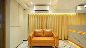 Una habitación con sofá, aire acondicionado, cortina y suelo de diseño de mármol.
