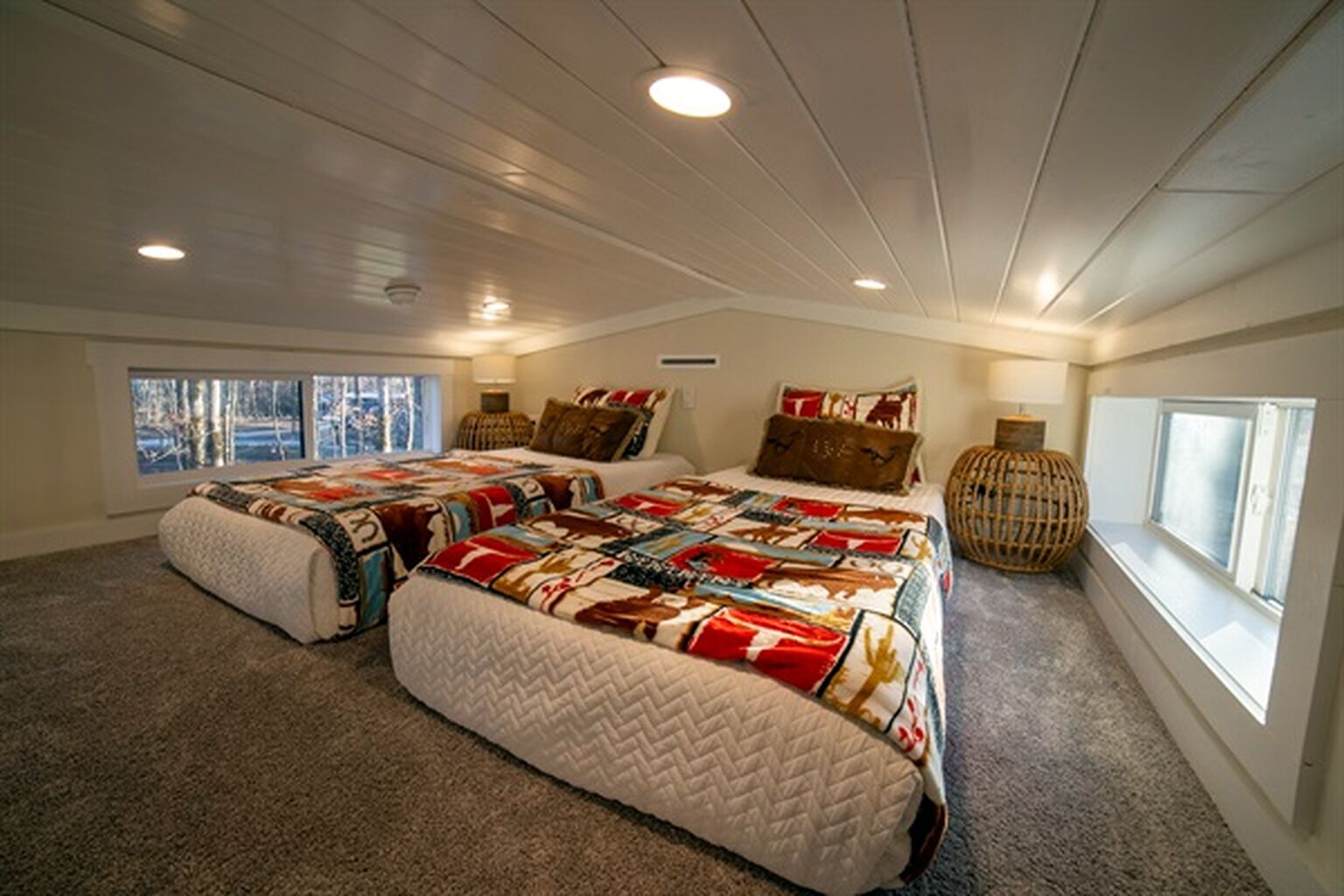 A bedroom with a large bed, two windows, and a ceiling with recessed lighting.