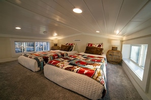 Ein Schlafzimmer mit einem großen Bett, zwei Fenstern und einer Decke mit Einbauleuchten.