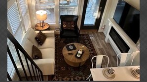 Ein Wohnzimmer mit einer Couch, einem runden Couchtisch, einem Sessel und einem Fernseher.