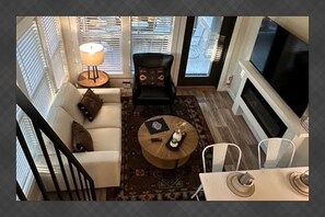 Una sala de estar con un sofá, una mesa redonda de centro, una silla y un televisor.