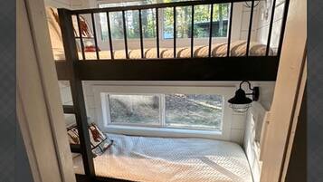 A bunk bed with a window, a hanging light fixture, and a view of the outdoors.