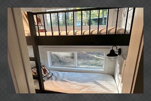 Een stapelbed met een raam, een hanglamp en uitzicht op de omgeving.