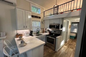 Una cocina con una isla central, electrodomésticos de acero inoxidable y un letrero que dice 'TAKE A HIK'.