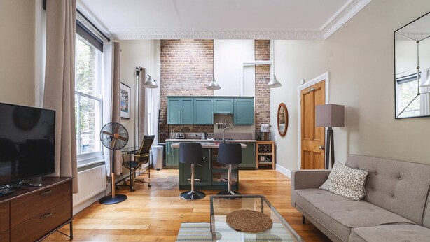 A modern living room with a TV, sofa, and a dining area with chairs and a table. - Charming One-Bed Oasis in Hammersmith (London)