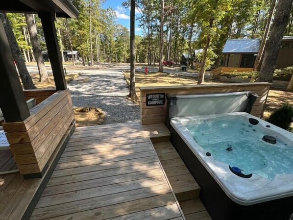 A wooden deck leading to a hot tub with a sign that reads "Life is better in a campfire."
