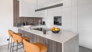 Une cuisine moderne avec un îlot central, des tabourets de bar et un saladier rempli de fruits.