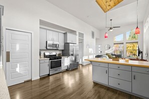 A modern kitchen with stainless steel appliances, grey cabinetry, and a wooden ceiling.