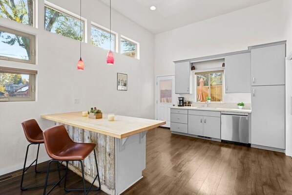 A modern kitchen with a wooden island, bar stools, and pendant lights.