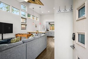 A modern living room with a grey sectional sofa, a foosball table, and a flat-screen TV.
