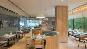 Un restaurant modern amb taules rodones, cadira amb amortidor i llums penjants.