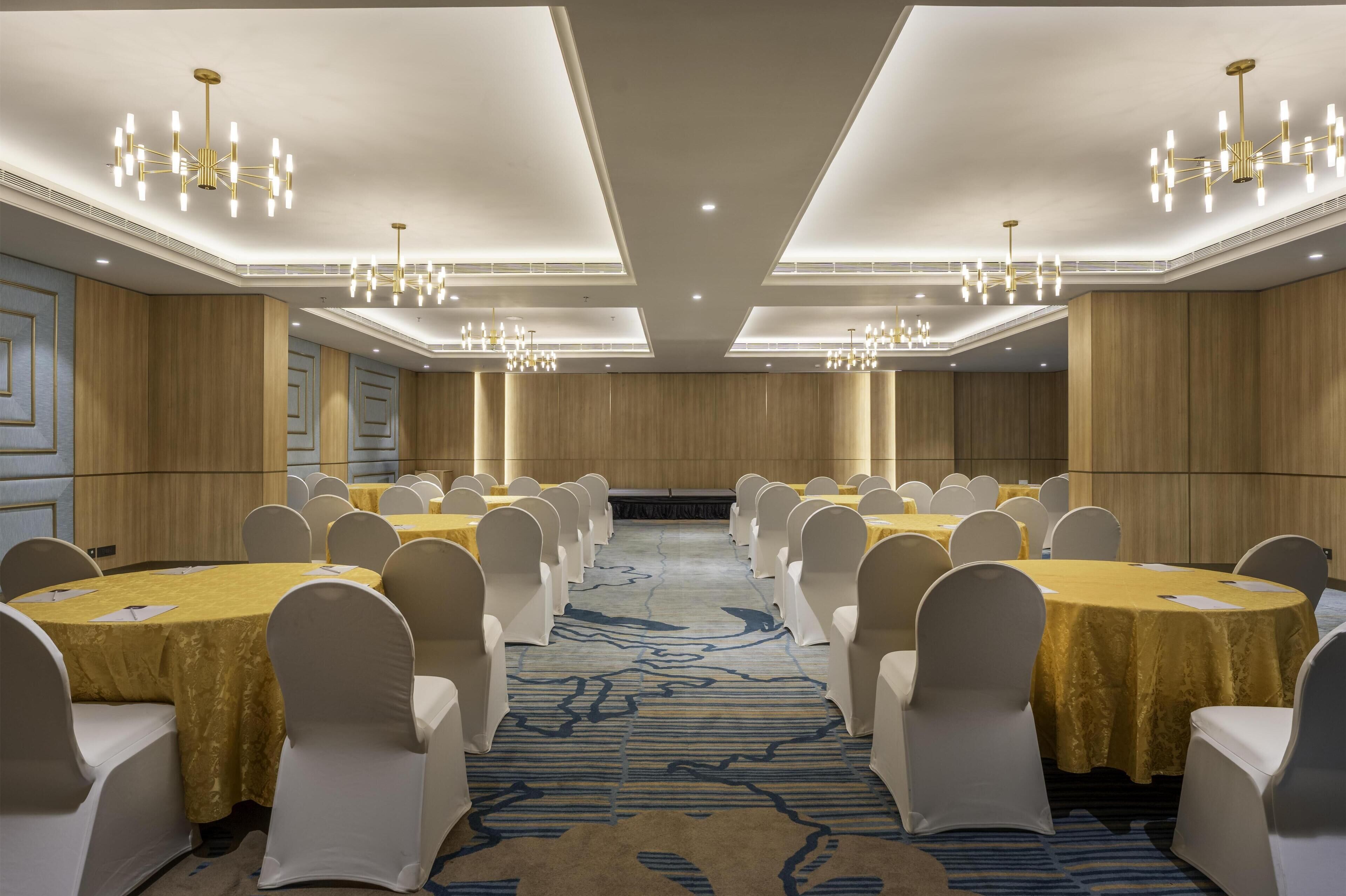 A conference room with multiple tables, chairs, and chandeliers.