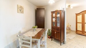 A dining area with a wooden table, chairs, a cabinet, and a bed in the background. - Pearl of Vesuvius  (Napoli)