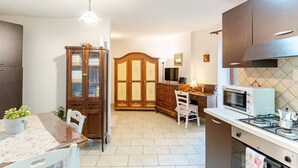 A compact kitchen with a dining area, wooden cabinets, a microwave, and a gas stove. - Pearl of Vesuvius  (Napoli)
