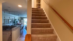 Eine Treppe mit Teppichstufen und einem hölzernen Geländer, das zu einer oberen Etage führt.