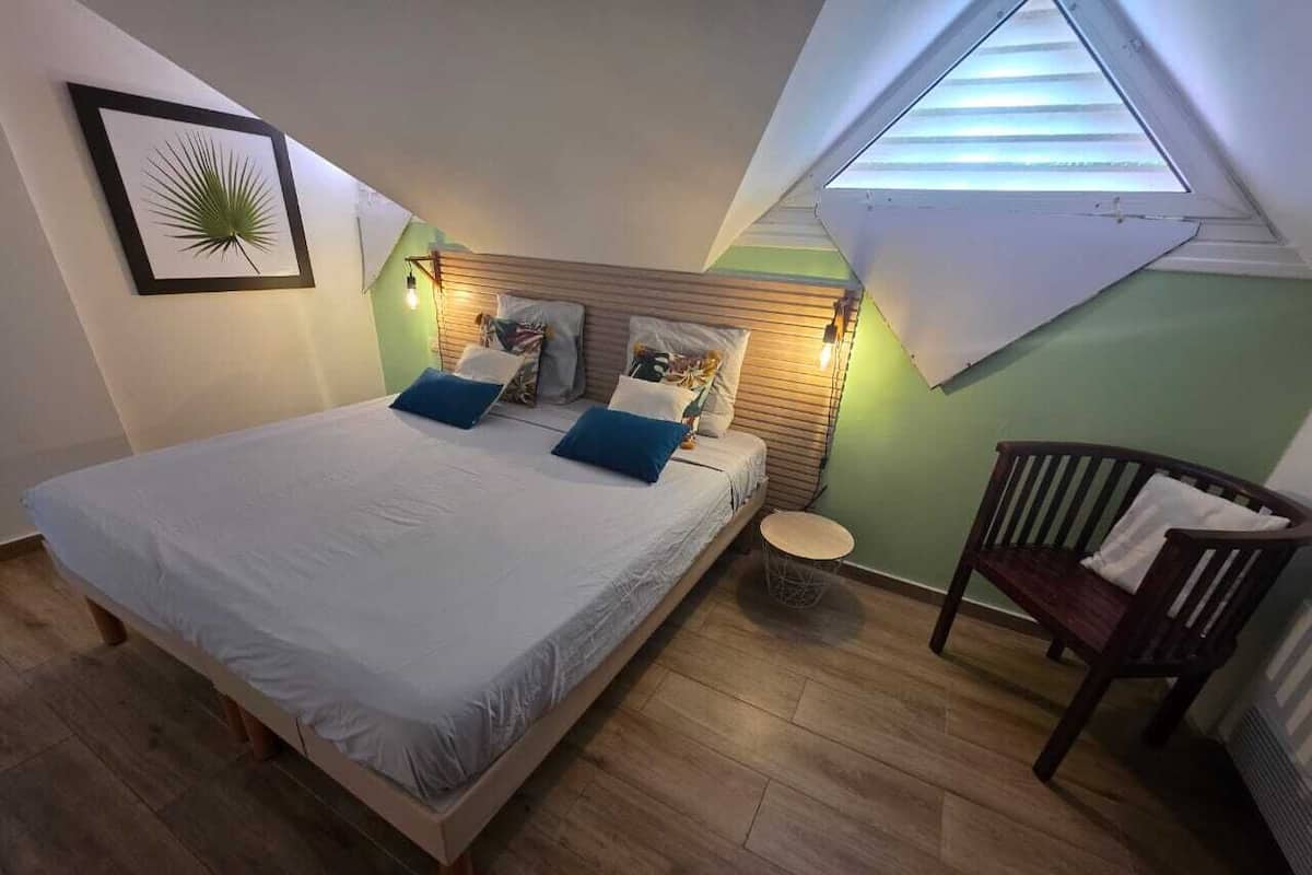 A bedroom with a bed, a chair, a small round table, and a skylight.