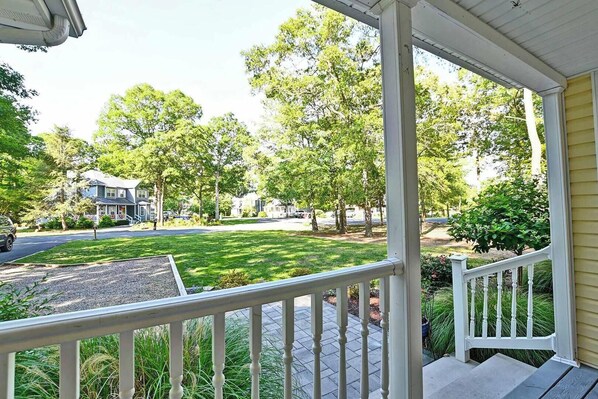 A porch with a view of a residential street, a lawn, and trees. - Community Pool, Sleeps 11! (Ocean View)
