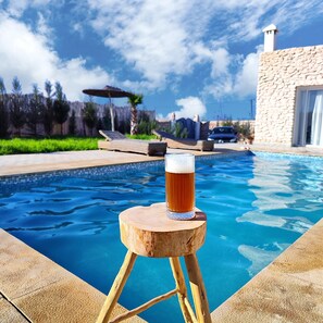 Et træbænk med et glas øl ved en pool.
