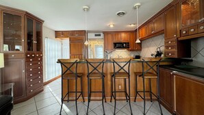 A kitchen with wooden cabinets, a central island with bar stools, and pendant lighting.