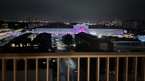 Vista nocturna de un paisaje urbano con edificios iluminados y una estructura destacada con techo iluminado en morado.