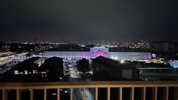 A nighttime view of a cityscape with illuminated buildings and a prominent structure with a purple-lit roof.