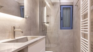 Un baño moderno con lavamanos, inodoro y ducha.