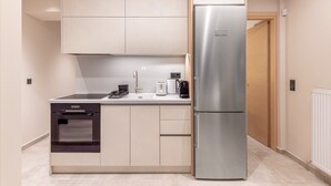 Una cocina compacta con horno integrado, un refrigerador de acero inoxidable y una cafetera sobre la encimera.