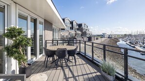 A balcony with a table and chairs, overlooking a marina with boats. - Luxe Appartement Vista Maris Somaris - Havenweg 8-50 Sint-annaland Oosterschelde (Sint-Annaland)