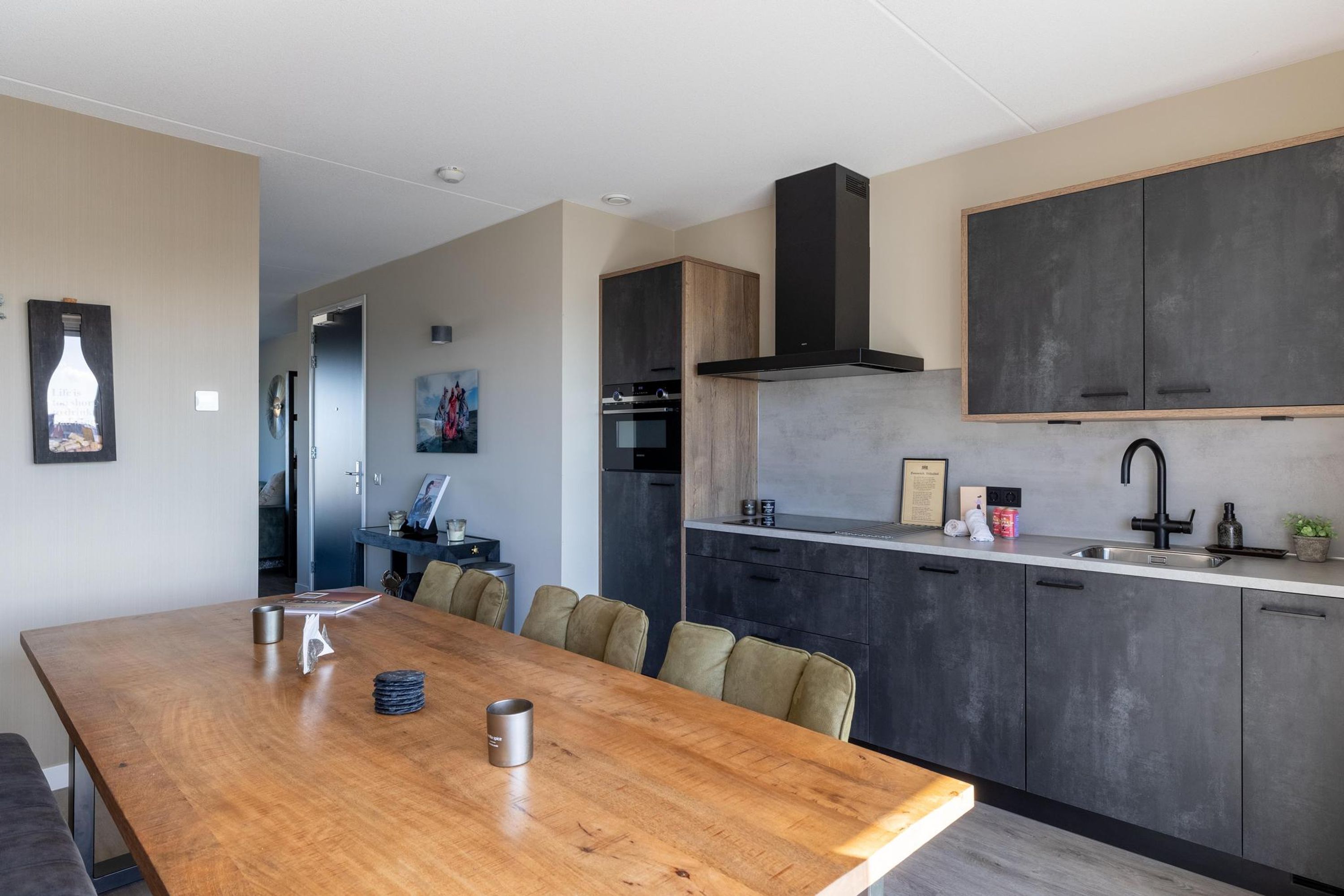Una cucina moderna con pensili scuri, un tavolo da pranzo in legno e un'ampia finestra.