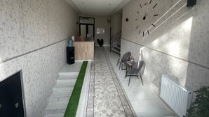 Ein Flur mit einer Rezeption, einer Treppe und einer Sitzecke mit Stühlen.