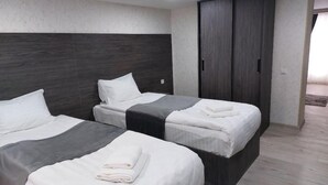 Ein Hotelzimmer mit zwei Betten, einem dunklen Holz-Kopfteil, einem Kleiderschrank und einem hellen Boden.