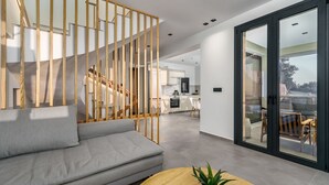 Una sala de estar moderna con un sofá gris, suelo de madera y una escalera con barandilla de madera.