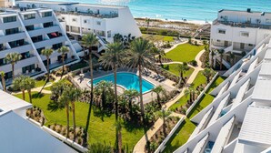 A modern hotel with a pool surrounded by palm trees and a view of the ocean. - Aegean 102 2 Bedroom Condo (Destin)