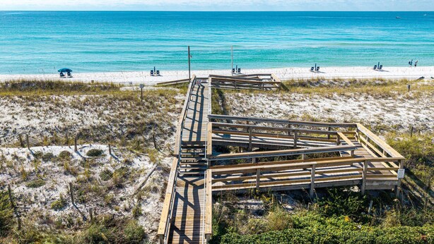 A wooden boardwalk leading to a beach with clear blue water and a sandy shore. - Aegean 102 2 Bedroom Condo (Destin)
