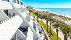 A hotel with a white facade, a beach view, and a sandy walkway. - Aegean 102 2 Bedroom Condo (Destin)