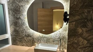 Une salle de bain avec un meuble-lavabo en bois, un lavabo rectangulaire, un miroir avec éclairage intégré et des toilettes.