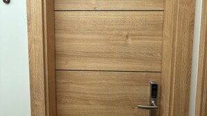 Une porte en bois dotée d’un clavier pour l’ouverture, le chiffre « 6 » peint sur le mur, et un cadre blanc encadrant le chambranle de la porte.